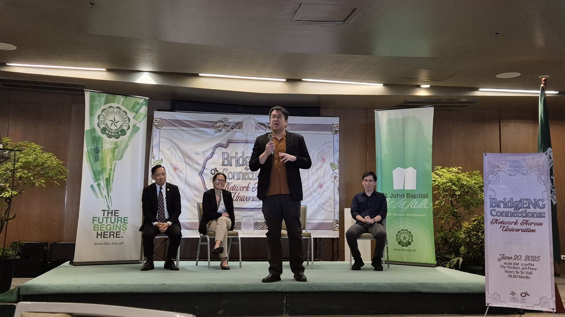 Charles Lu speaking at the BridgENG Connections forum at DLSU, with three professors seated behind him