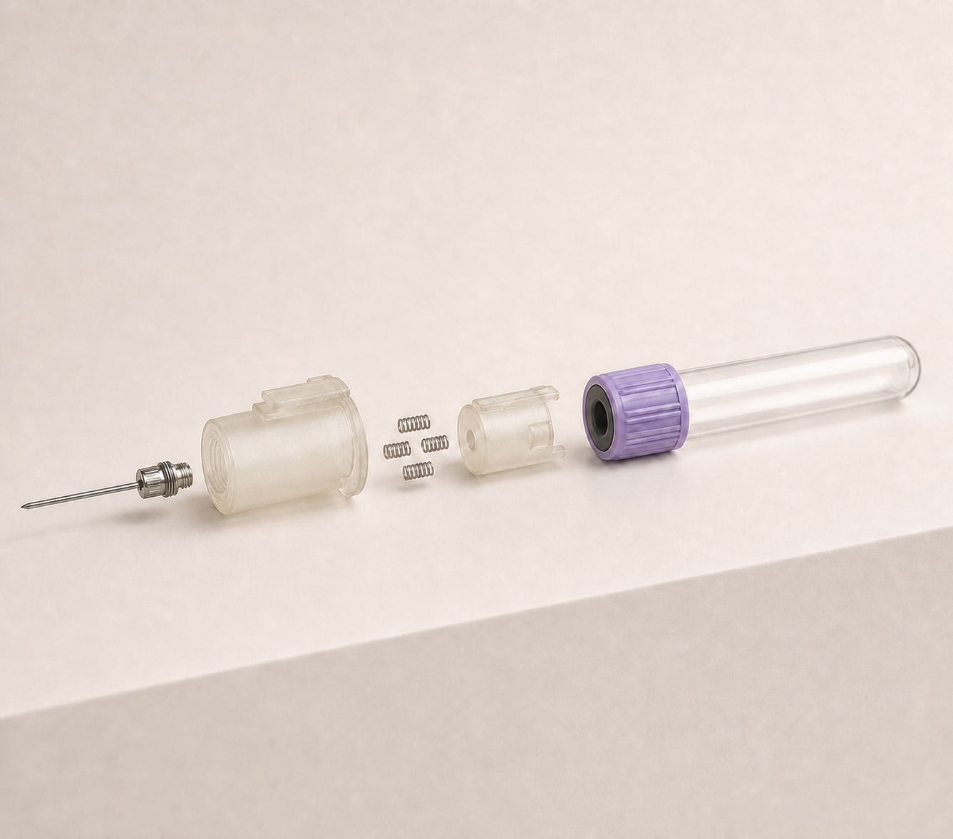 Exploded view showing the threaded needle hub, matching housing socket, four compression springs, ejector carrier, and standard Vacutainer tube